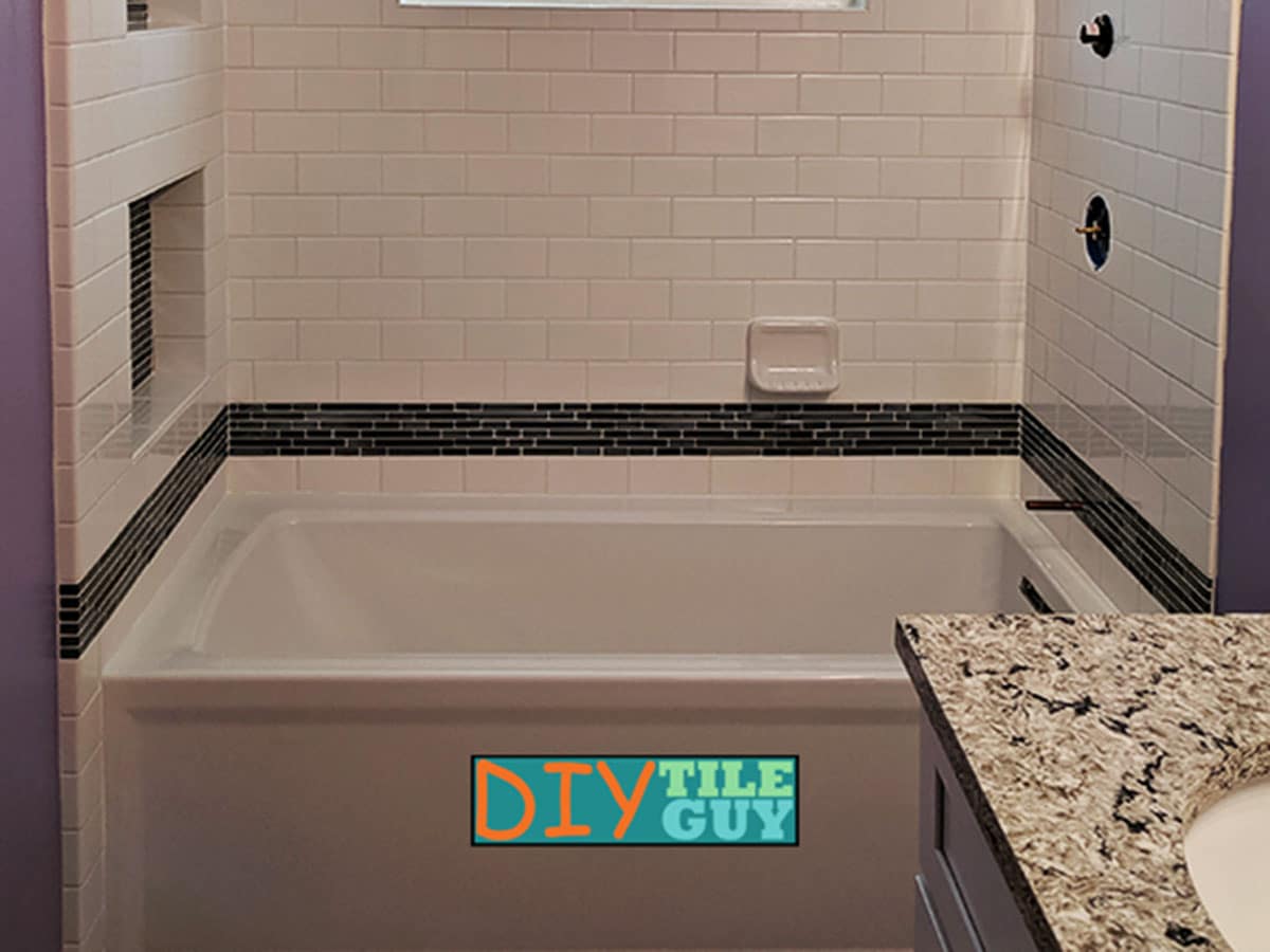 A tiled bathtub surround where one wall is built out and has a tile return