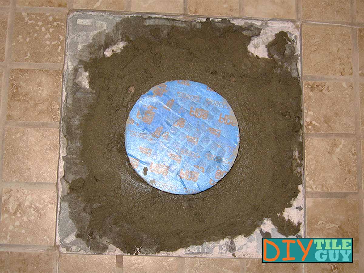 drypack mortar is reinstalled around shower pan drain