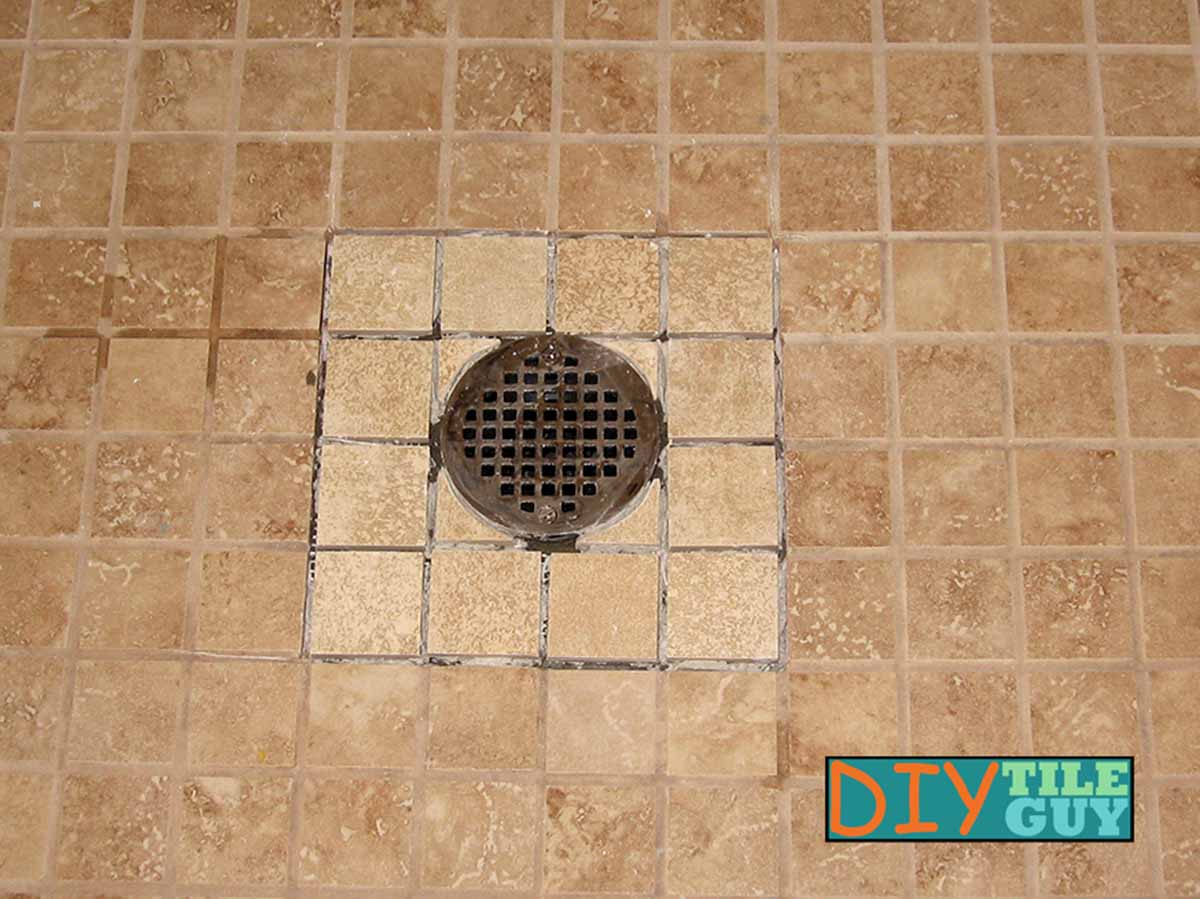 New tiles are cut and reinstalled around round shower drain